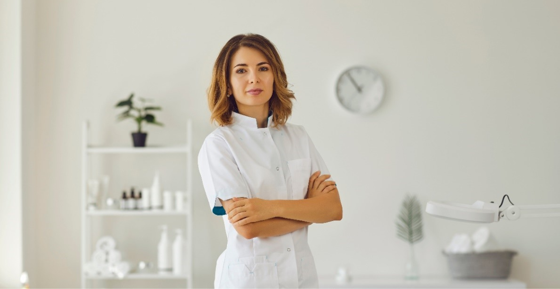 Woman in a white lab-coat standing in a white office.