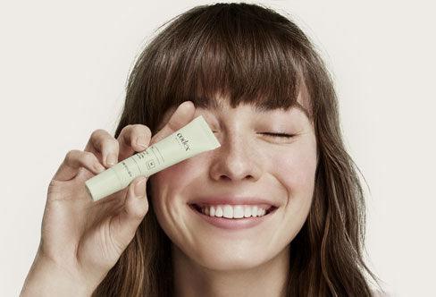 Codex Beauty Labs model holding a Bia Eye Cream up to their face.