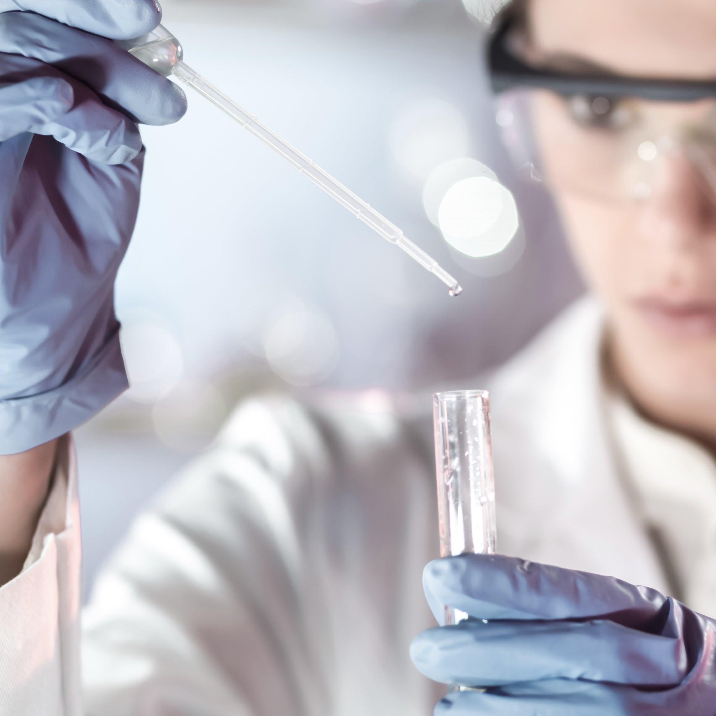 Image of scientist looking at a test tube and pipette