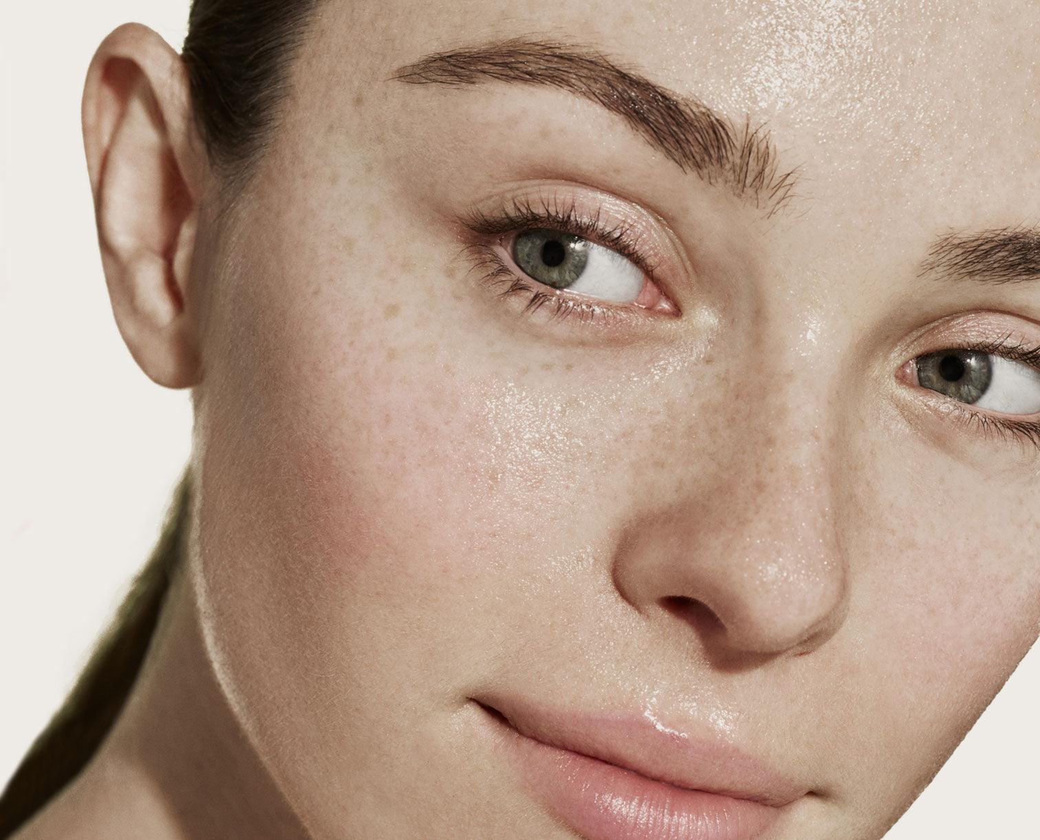 Close up image of a female model's face with a light pink background e m