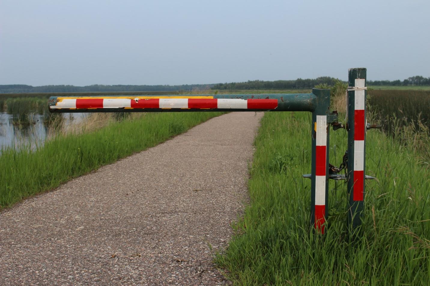 A road barrier near water with clear skies.