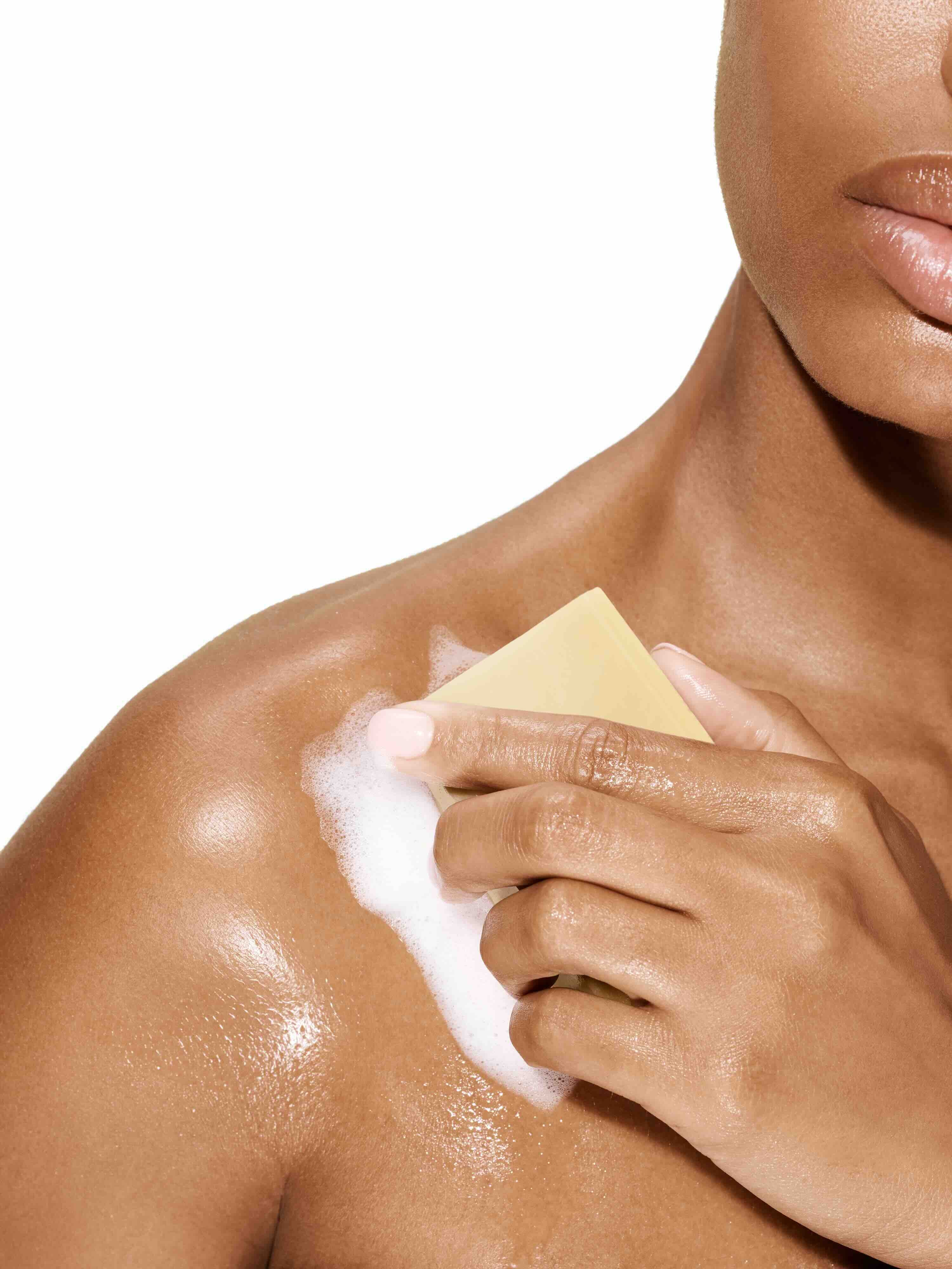 Image of a female model using a bar of Antü Refreshing Soap on her shoulder.