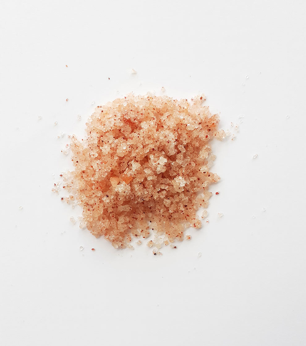 One pink  pile of salt side by side on a white background.